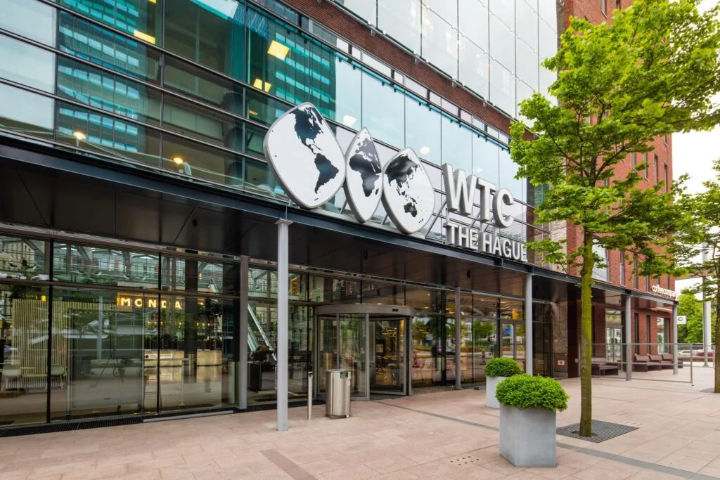 Ingang van het World Trade Center The Hague aan de Prinses Beatrixlaan met moderne glazen gevel en opvallend logo.